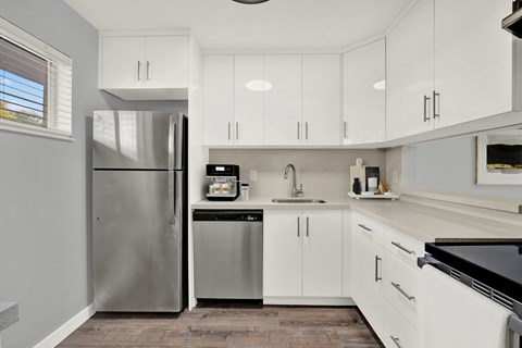 A modern kitchen with white cabinets and stainless steel appliances.