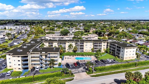 A large apartment complex with a pool in the middle of a parking lot.