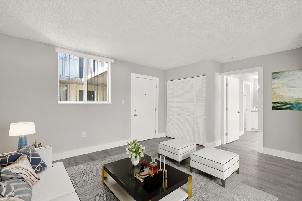 A living room with a grey carpet and a black coffee table.