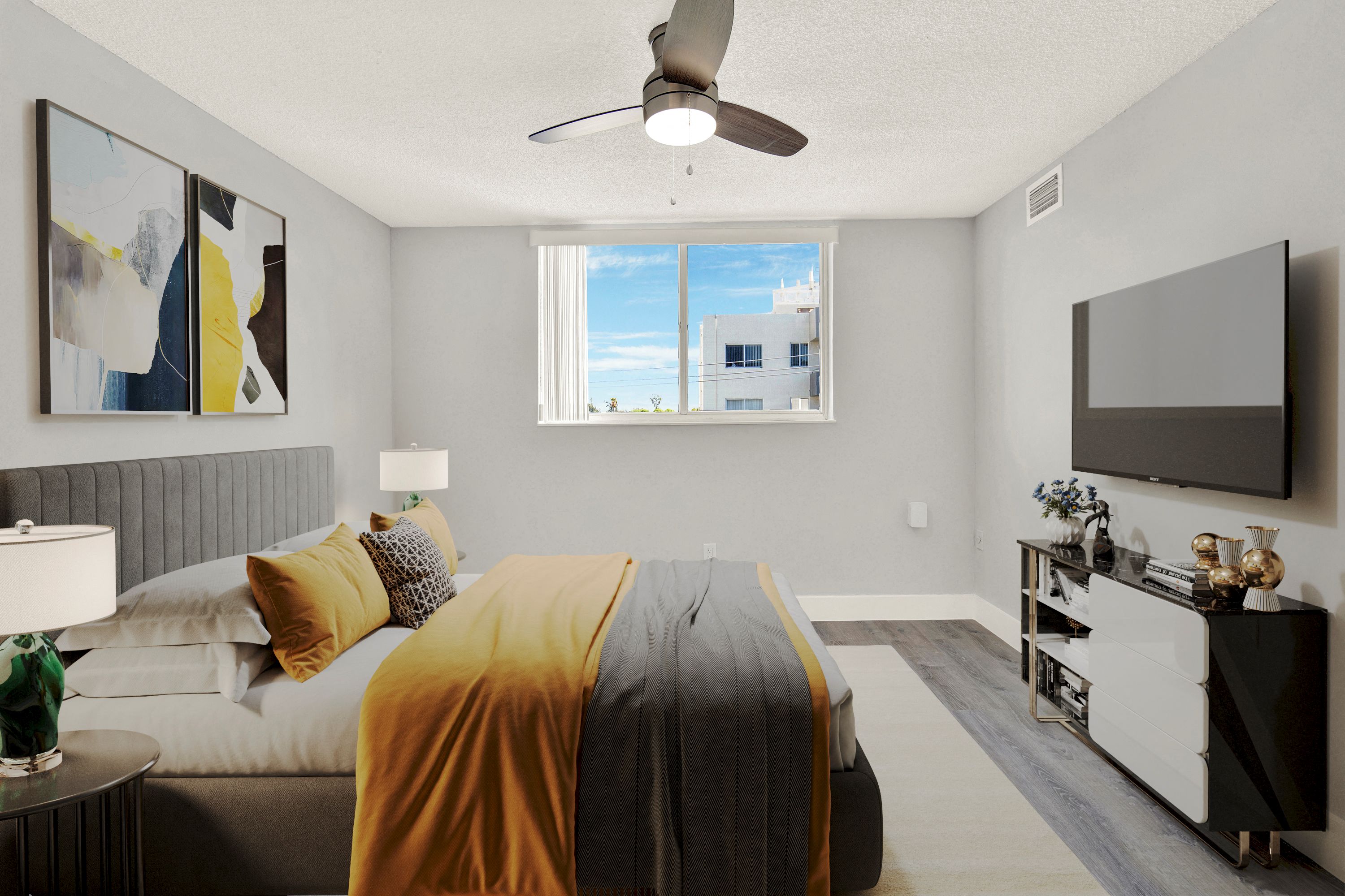A bedroom with a bed covered in a yellow blanket and a ceiling fan.