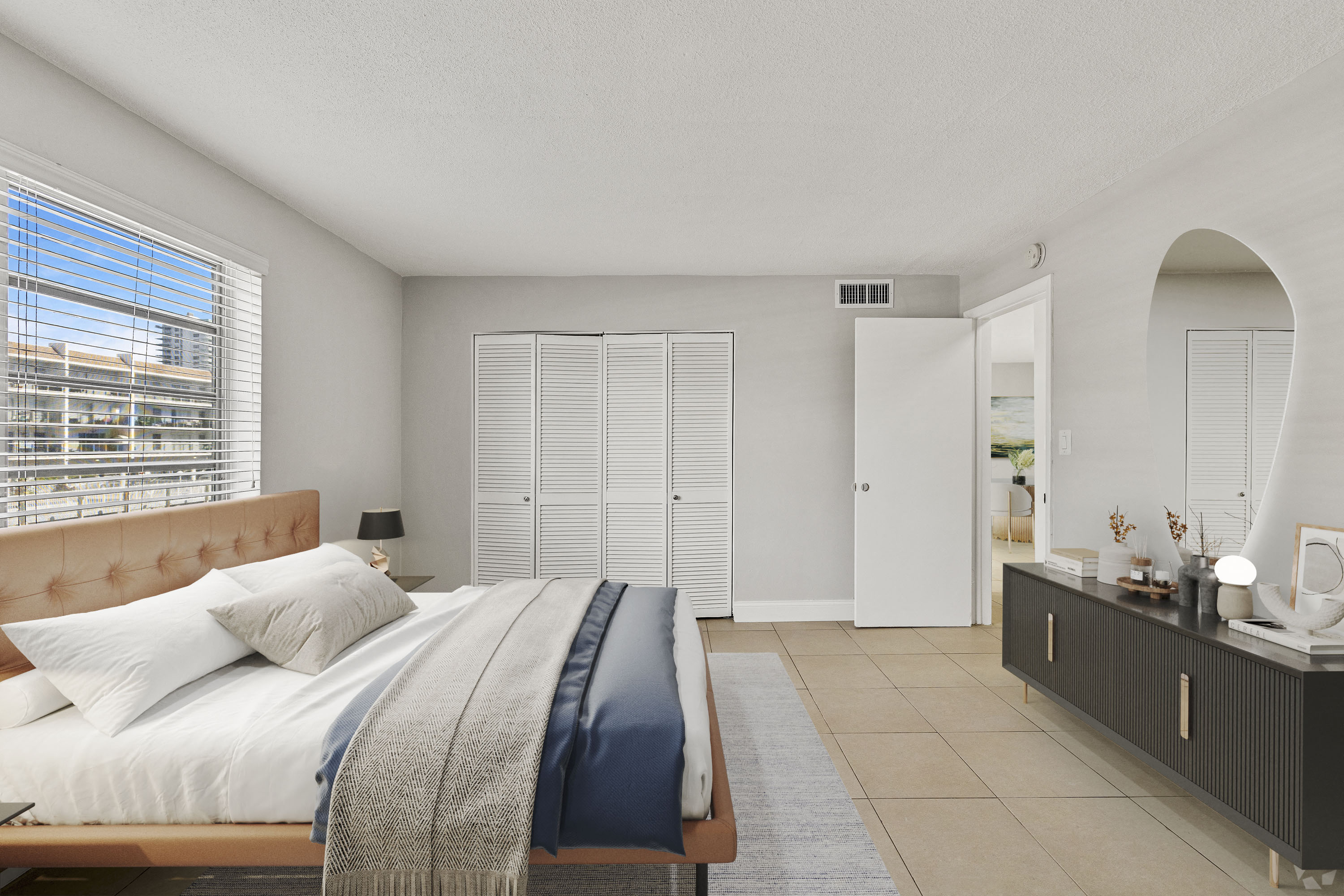 A bedroom with a large bed and a window with blinds.