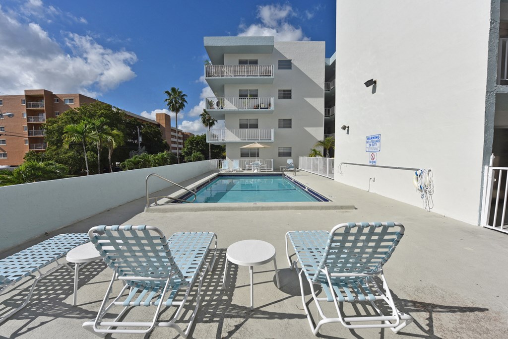 a swimming pool with blue and white chairs in front of a building