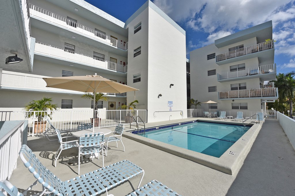 a swimming pool in the middle of a hotel patio with chairs and tables