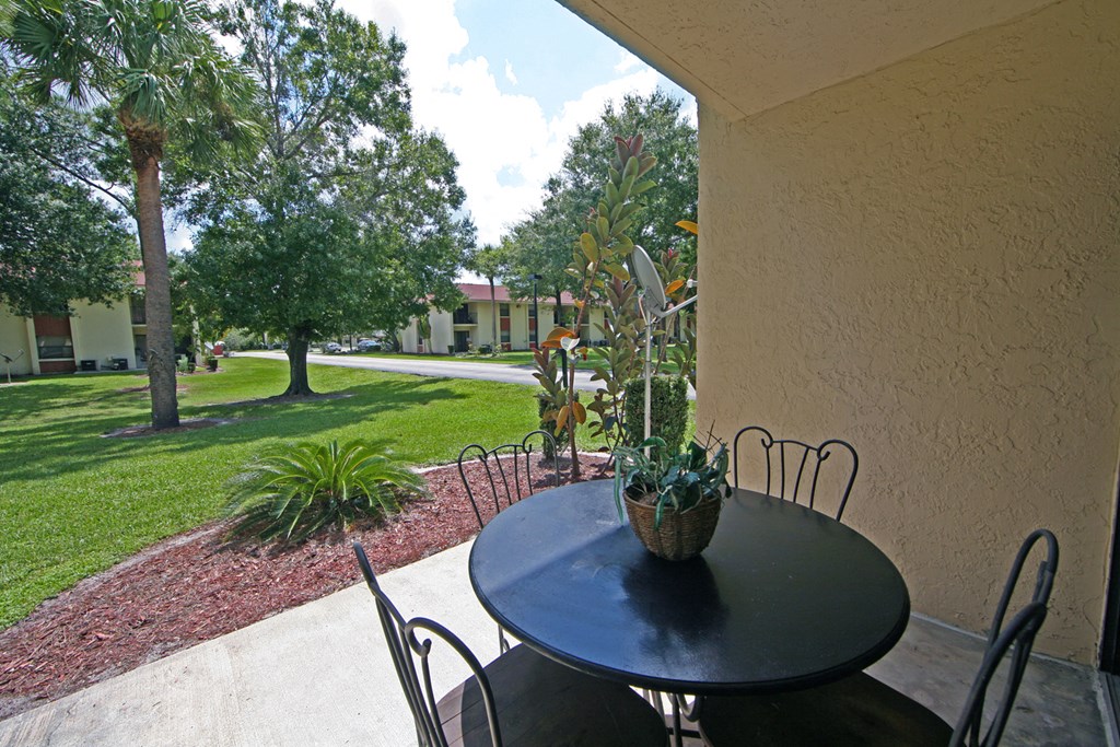 a patio with a table and chairs in front of a garden