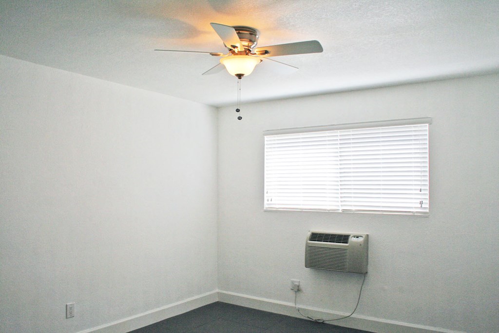 an empty room with a ceiling fan and a window