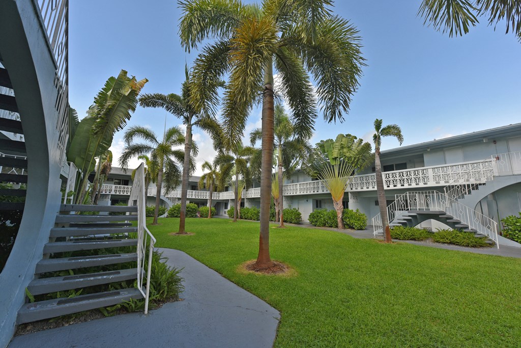 a courtyard with palm trees in front of a building