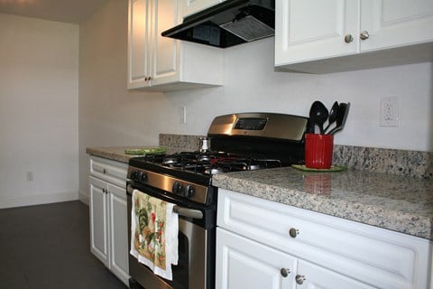 a kitchen with white cabinets and granite counter tops and a stainless steel stove and oven