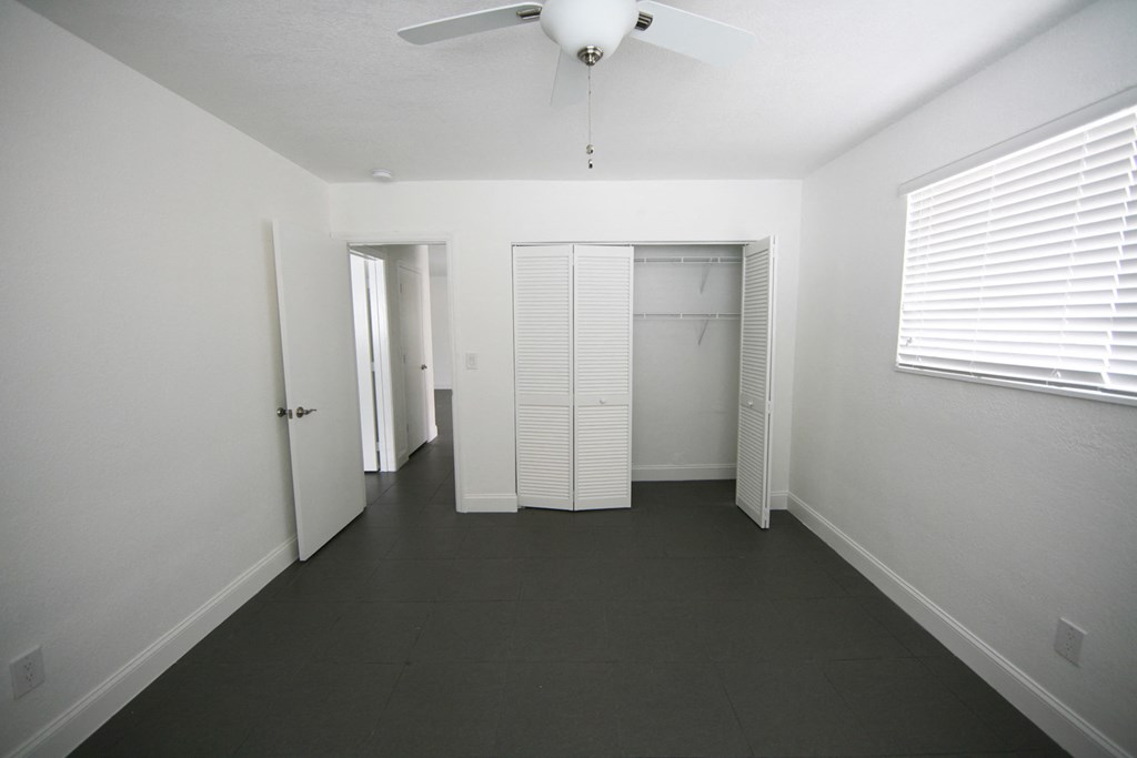 an empty room with a ceiling fan and a closet