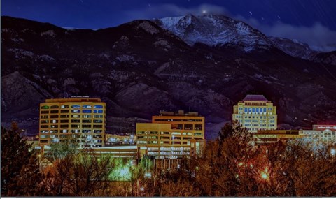 A cityscape at night with buildings and a mountain in the background.