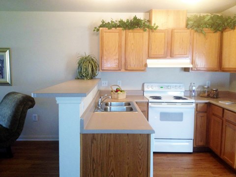 an empty kitchen with white appliances and wooden cabinets