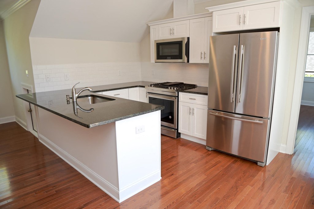 a kitchen with white cabinets and a stainless steel refrigerator