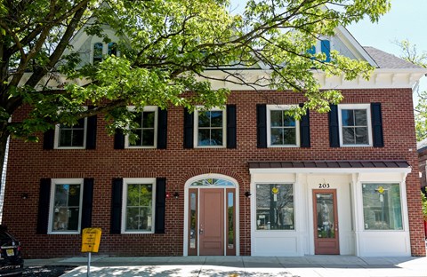 a red brick building with a brown door and a tree