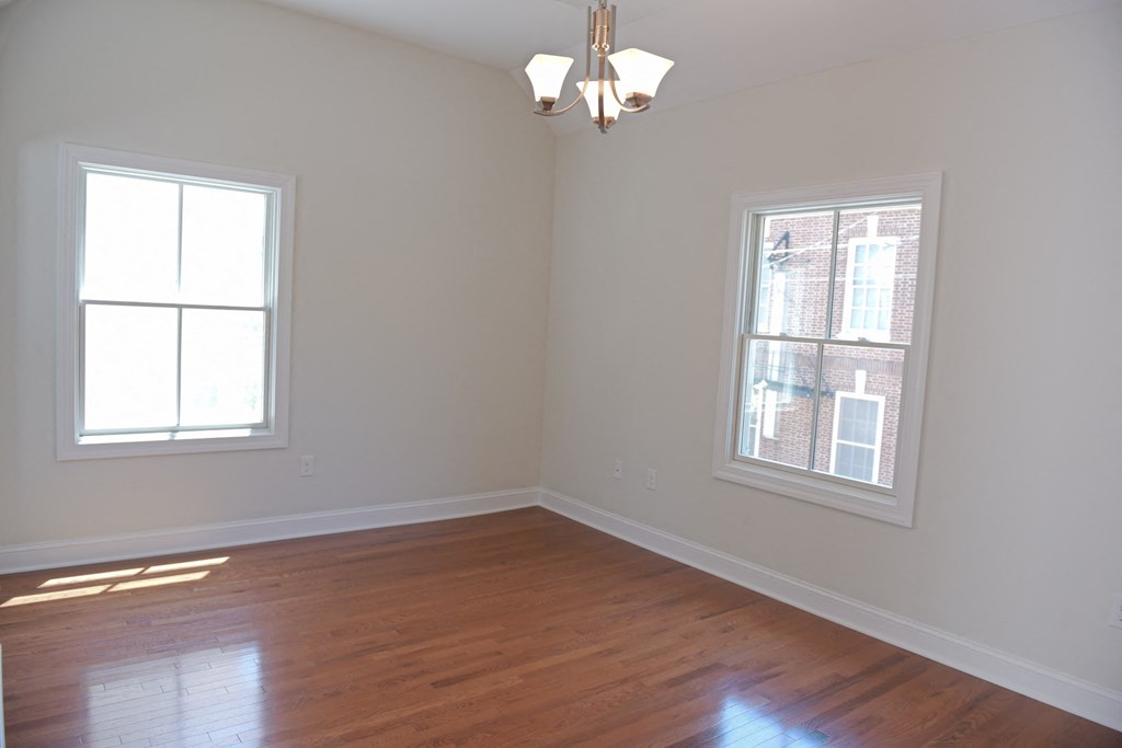 an empty room with two windows and a wooden floor