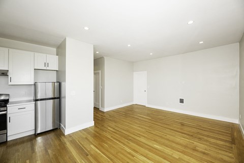 A kitchen with white cabinets and a wooden floor.