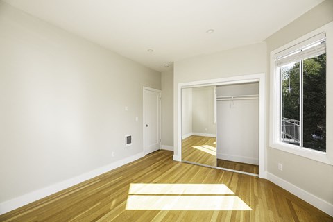 A room with a wooden floor and a large mirror on the wall.