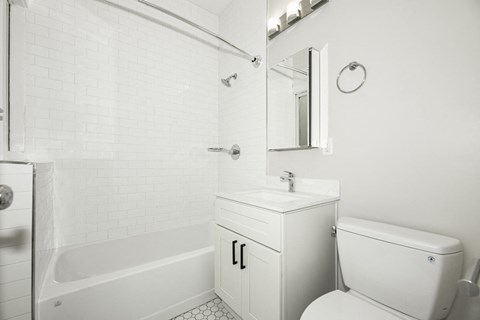 A white bathroom with a tub, sink, and toilet.