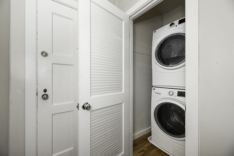 A white door is open to a small laundry room with a washer and dryer.