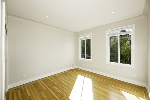 A room with wooden floors and two windows.