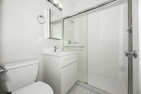 A white bathroom with a toilet, sink, and shower.