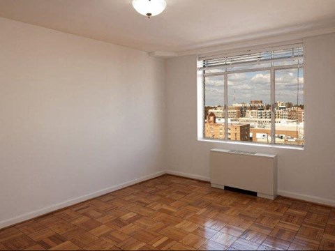 an empty room with a window and a wooden floor
