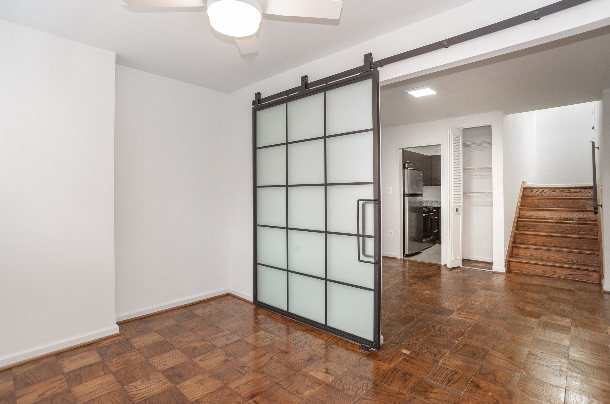 a living room with a staircase and a sliding glass door