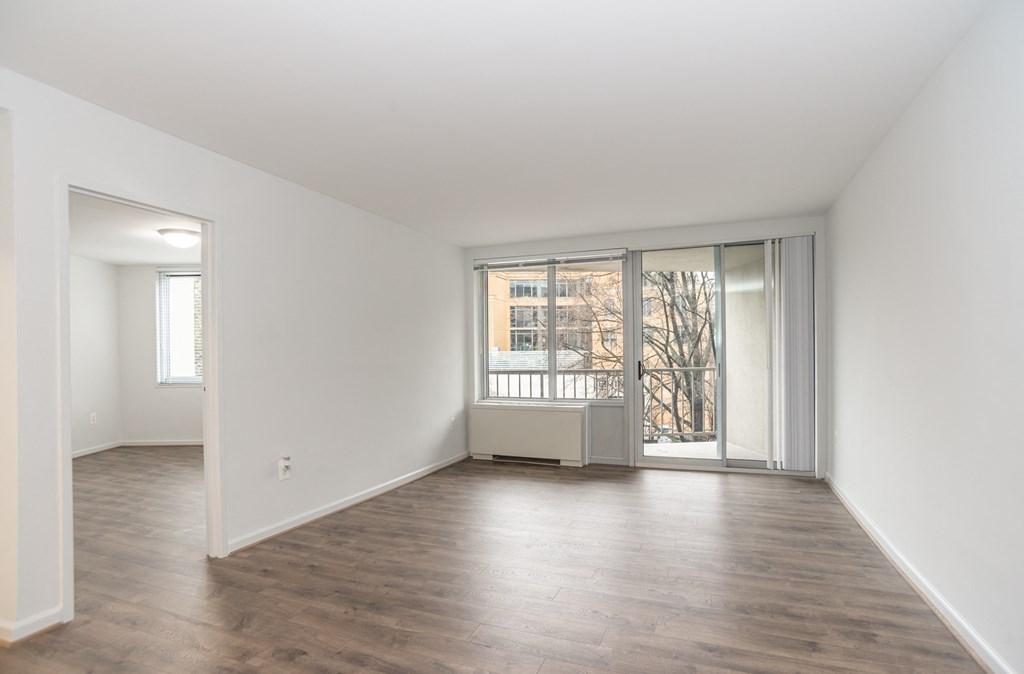 an empty living room with a large window and wood flooring