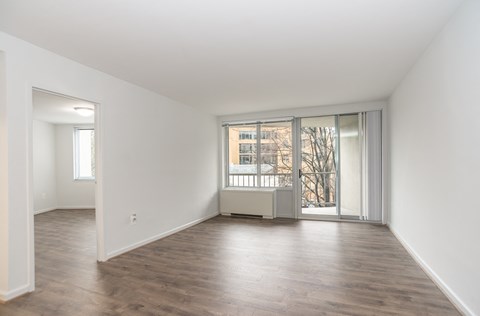 an empty living room with a large window and wood flooring