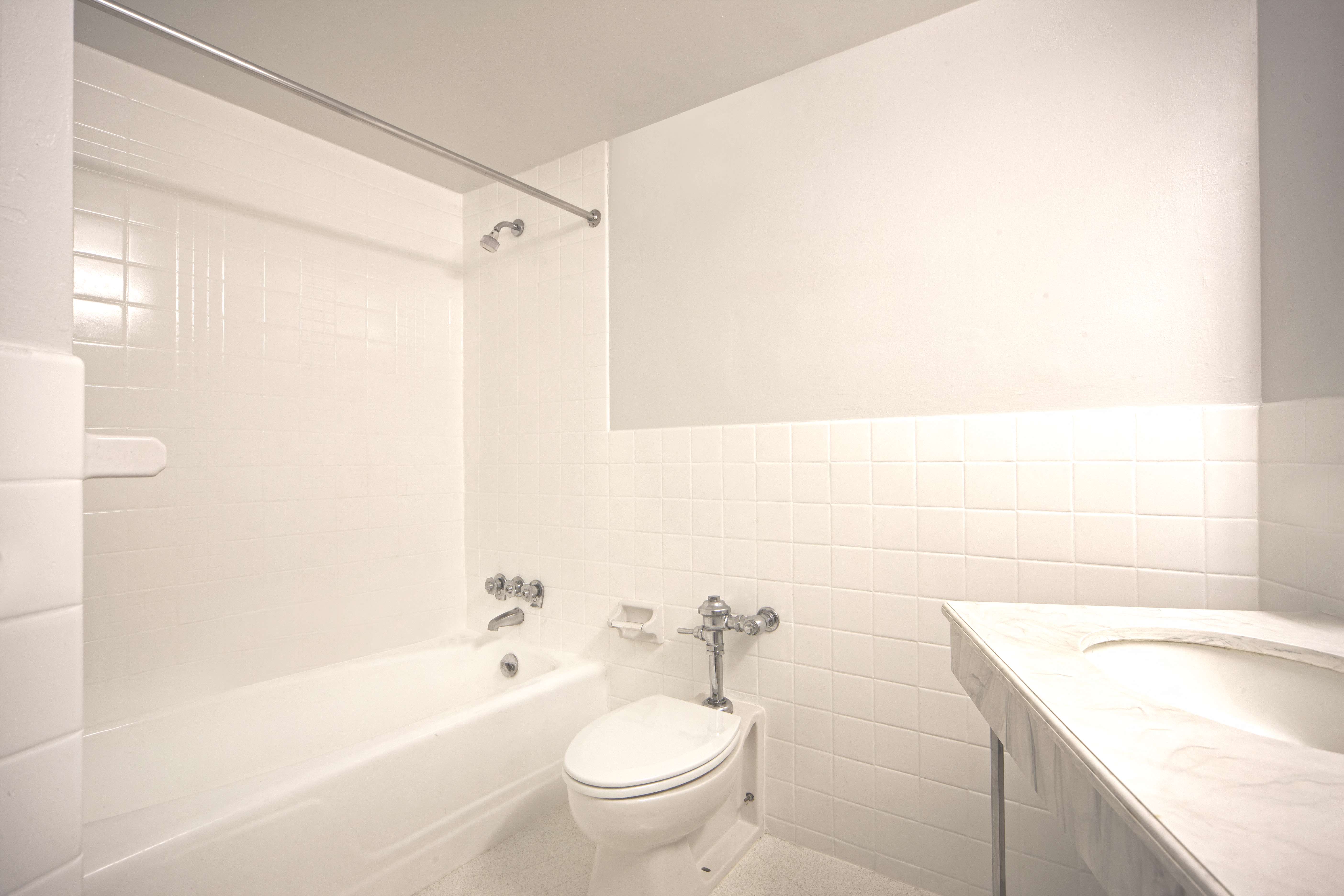 a white bathroom with a toilet and a tub and a sink