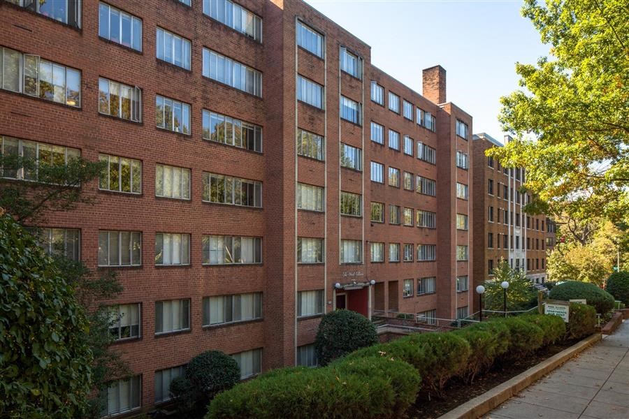 a large brick building with many windows and a sidewalk