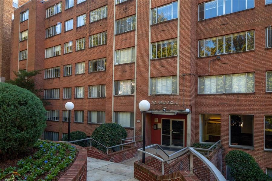 a brick apartment building with stairs and a red door