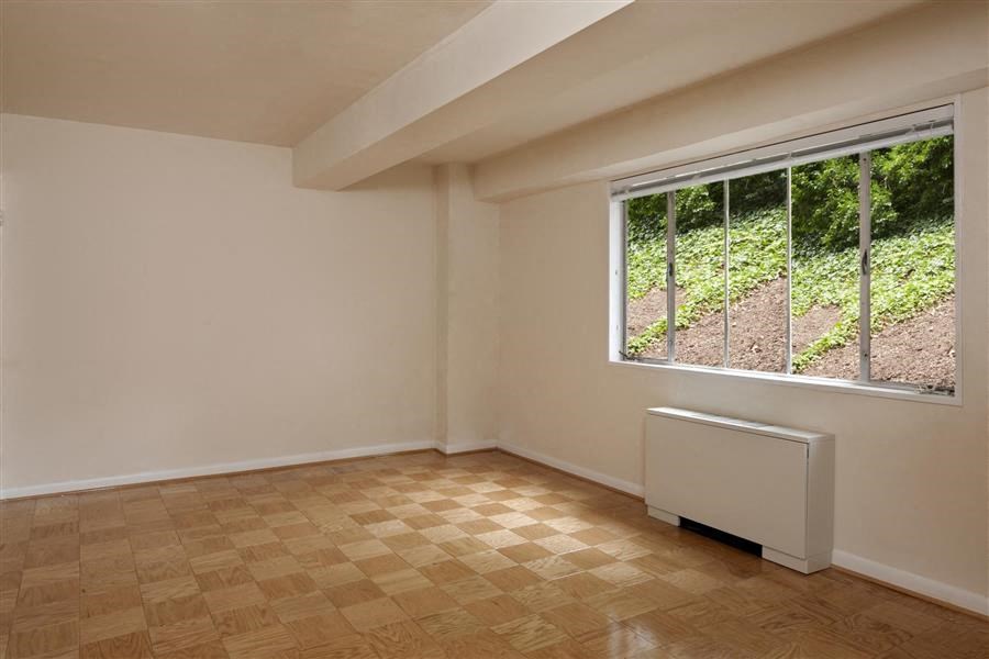 an empty room with a large window and wooden floors