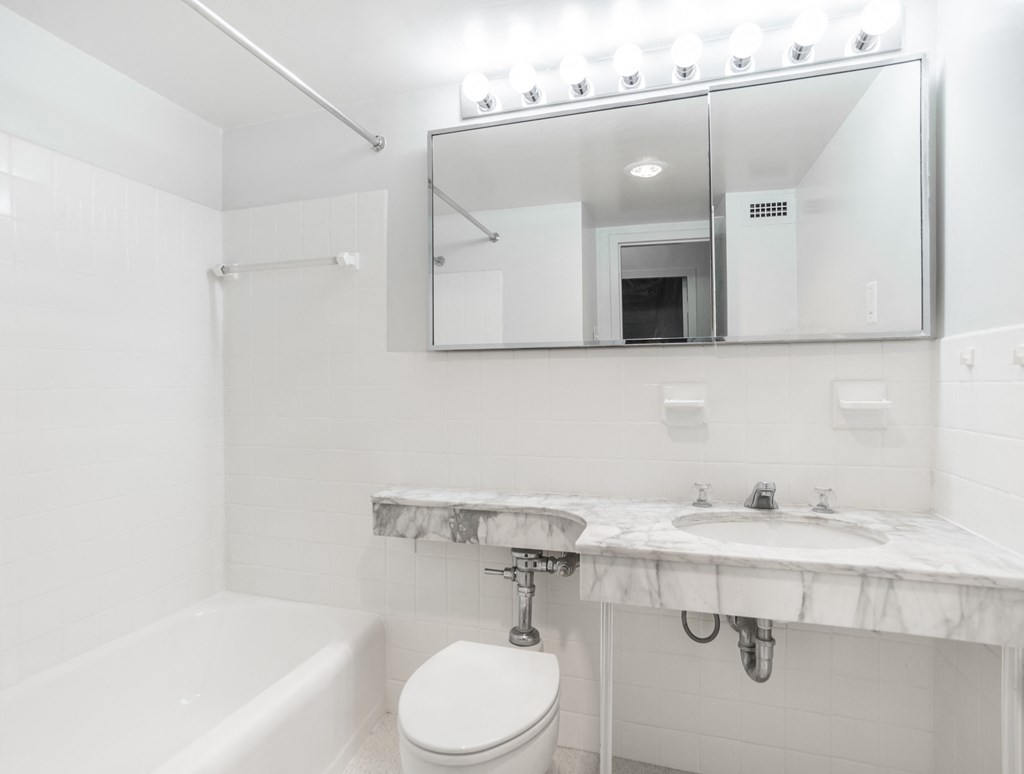 apartment bathroom with a tub shower and marble countertops
