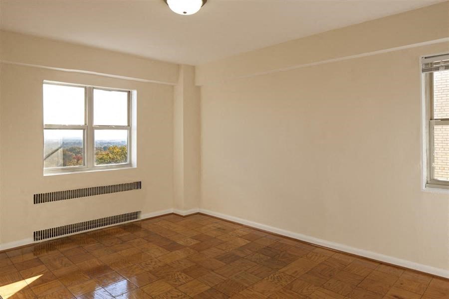 an empty room with a wooden floor and two windows