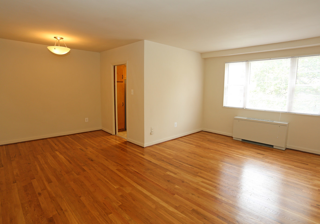 an empty living room with wood floors and a window