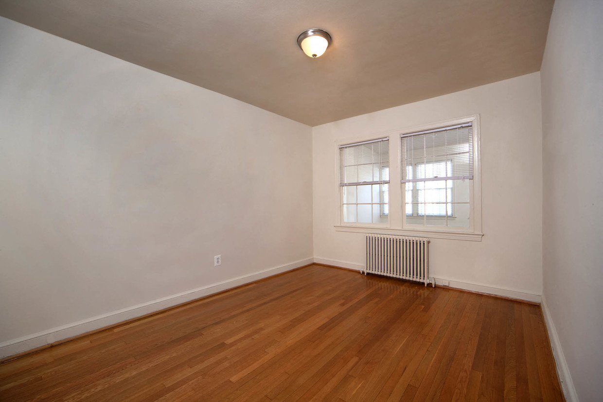 the living room of an empty home with wood floors and a window