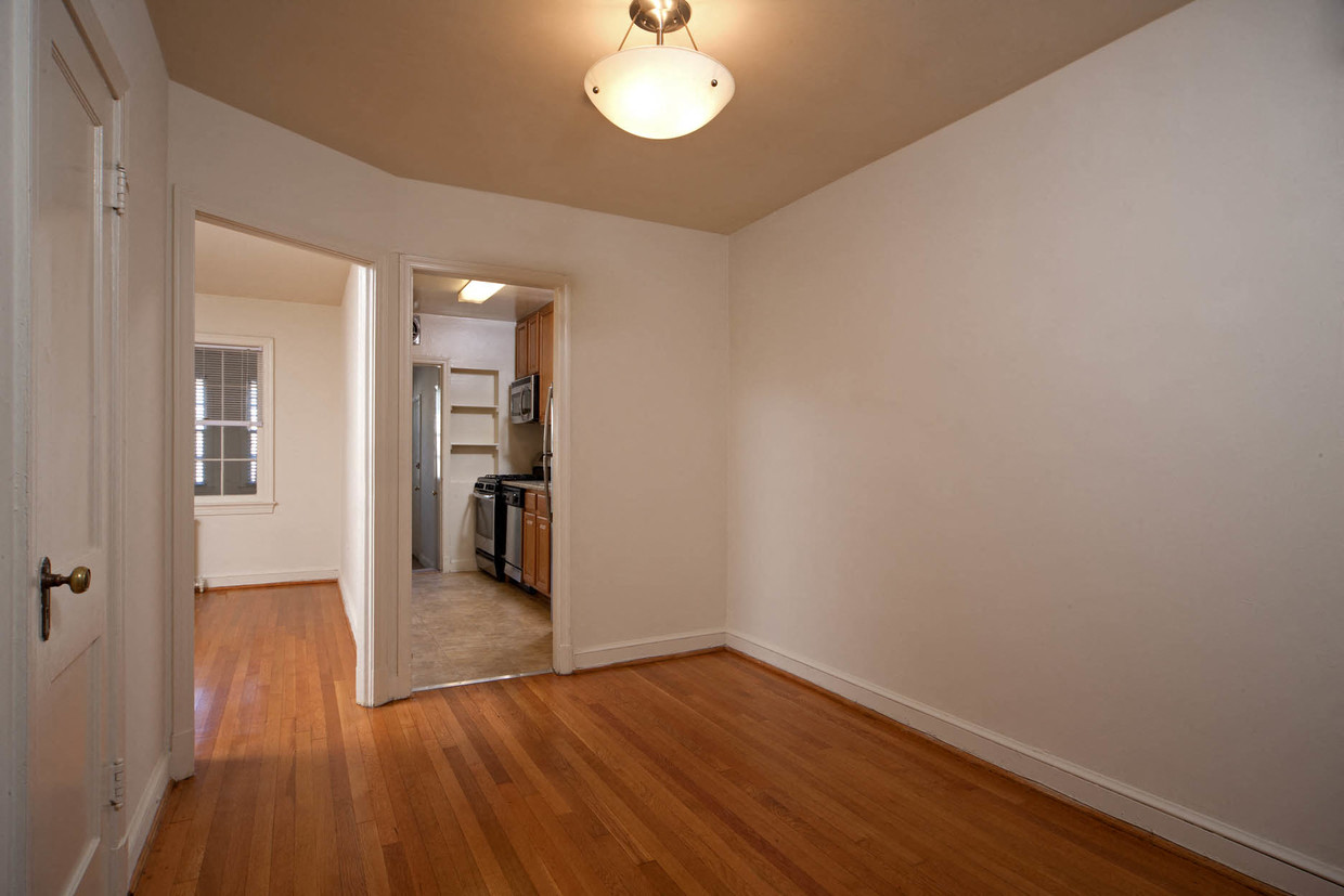 a living room with wood floors and a door to a kitchen