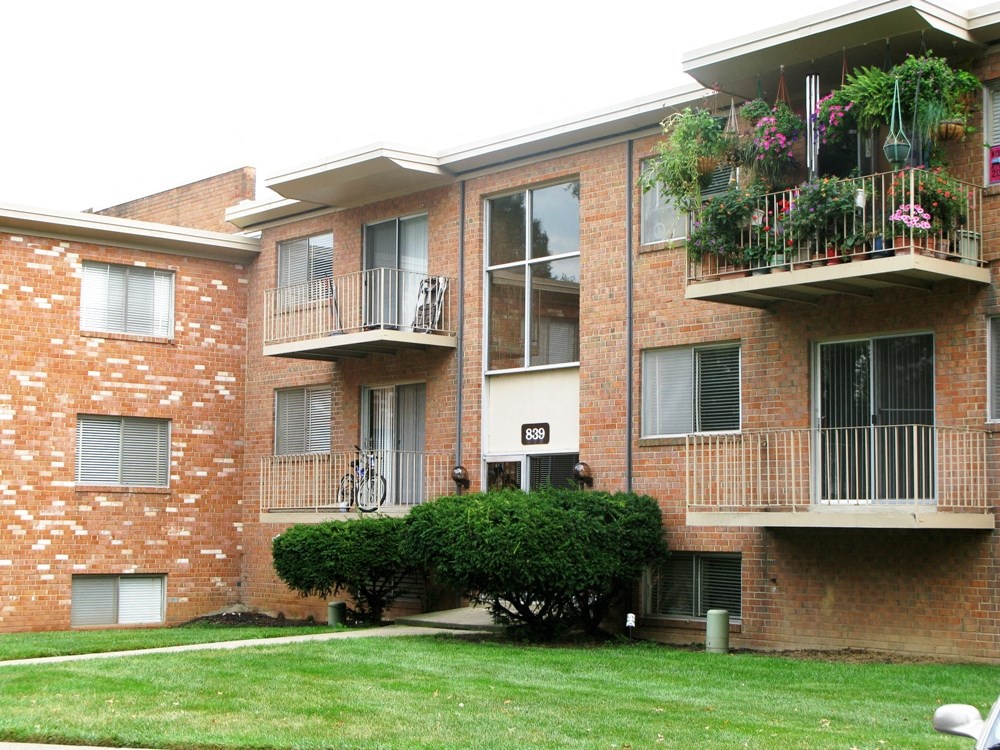 a brick apartment building with balconies and a lawn