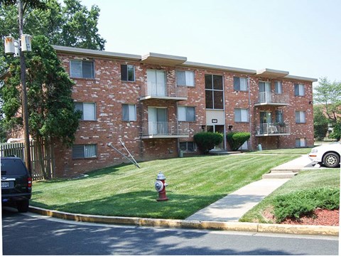 a red brick apartment building with a fire hydrant in the grass