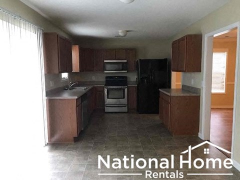 A kitchen with brown cabinets and black appliances is for rent.