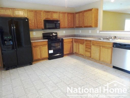 a kitchen with wooden cabinets and a black refrigerator