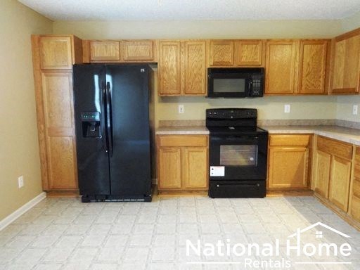 a kitchen with wooden cabinets and a black refrigerator