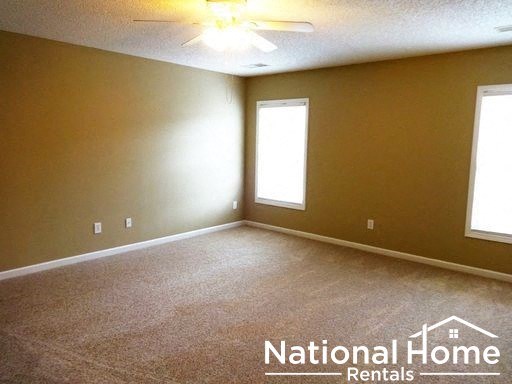 an empty room with a ceiling fan and two windows