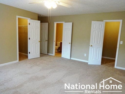an empty living room with three doors and a ceiling fan