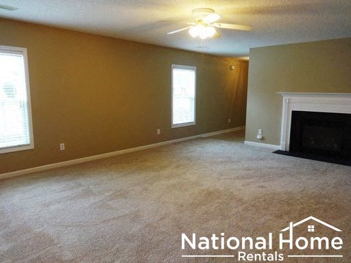 an empty living room with a fireplace and a ceiling fan