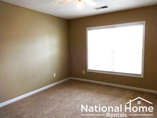 a bedroom with a window and a carpeted floor