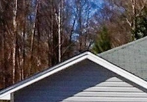 A house with a grey roof and a white garage door is for rent.