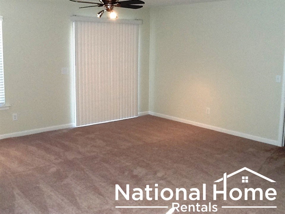 A room with a ceiling fan and a window with blinds.