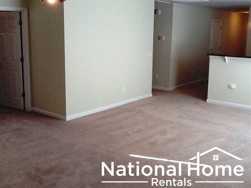 A room with a carpeted floor and a door on the left side.