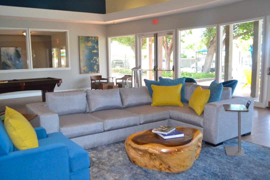 A living room with a blue couch and yellow pillows.