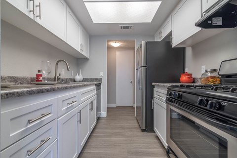 A kitchen with white cabinets and a black refrigerator.